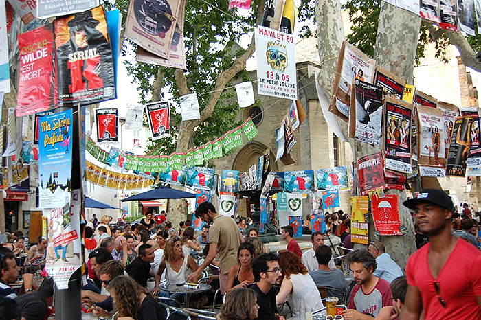 At the Avignon Festival, posters are affixed to walls, run as streamers, and hang from trees